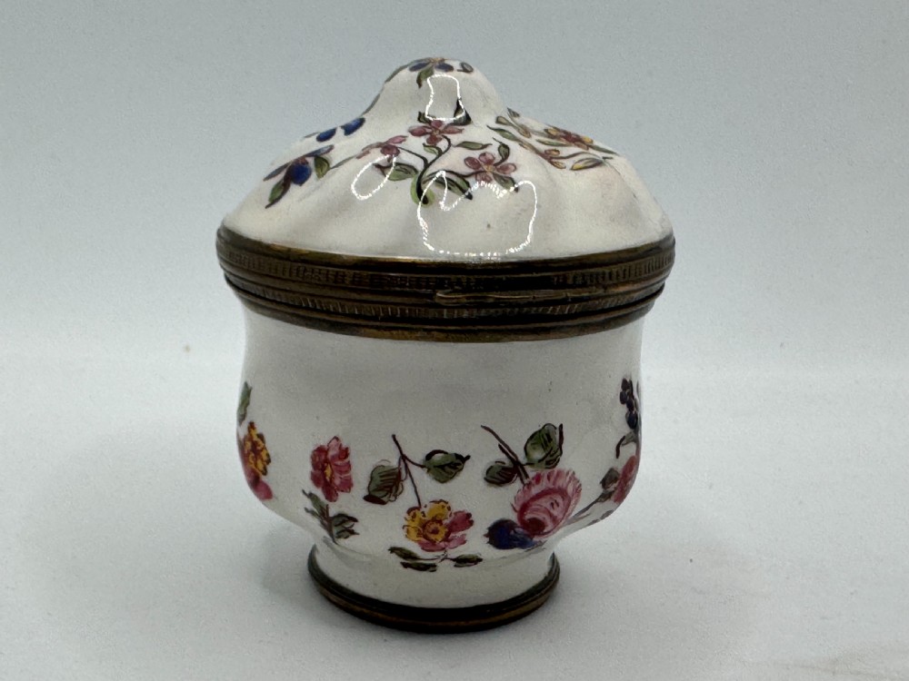 A white 18th-century Georgian Bilston enamel bonbonniere box decorated with hand-painted floral sprays and framed by brass metal mounts.