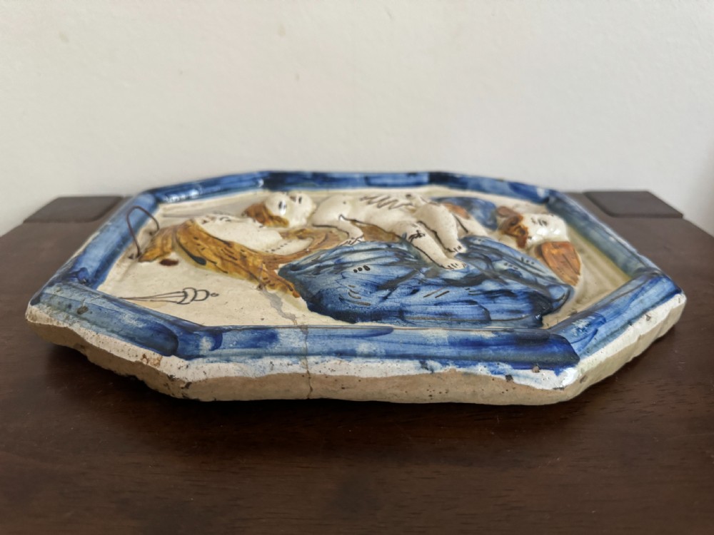 An octagonal 18th-century tin-glazed ceramic plaque depicting the Madonna holding the Christ Child in raised relief with blue and yellow accents. View VIII