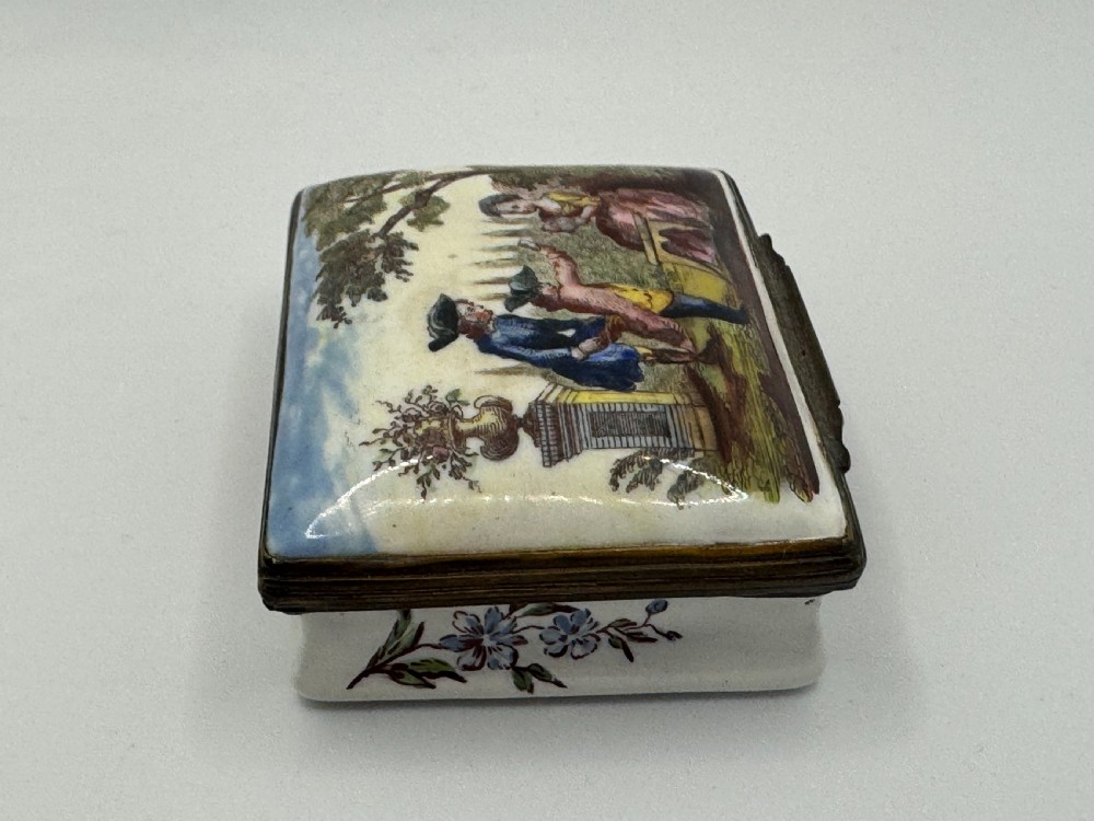 A rectangular 18th-century Bilston enamel box decorated with a painted pastoral scene on the lid and floral sprigs along the white base. View III