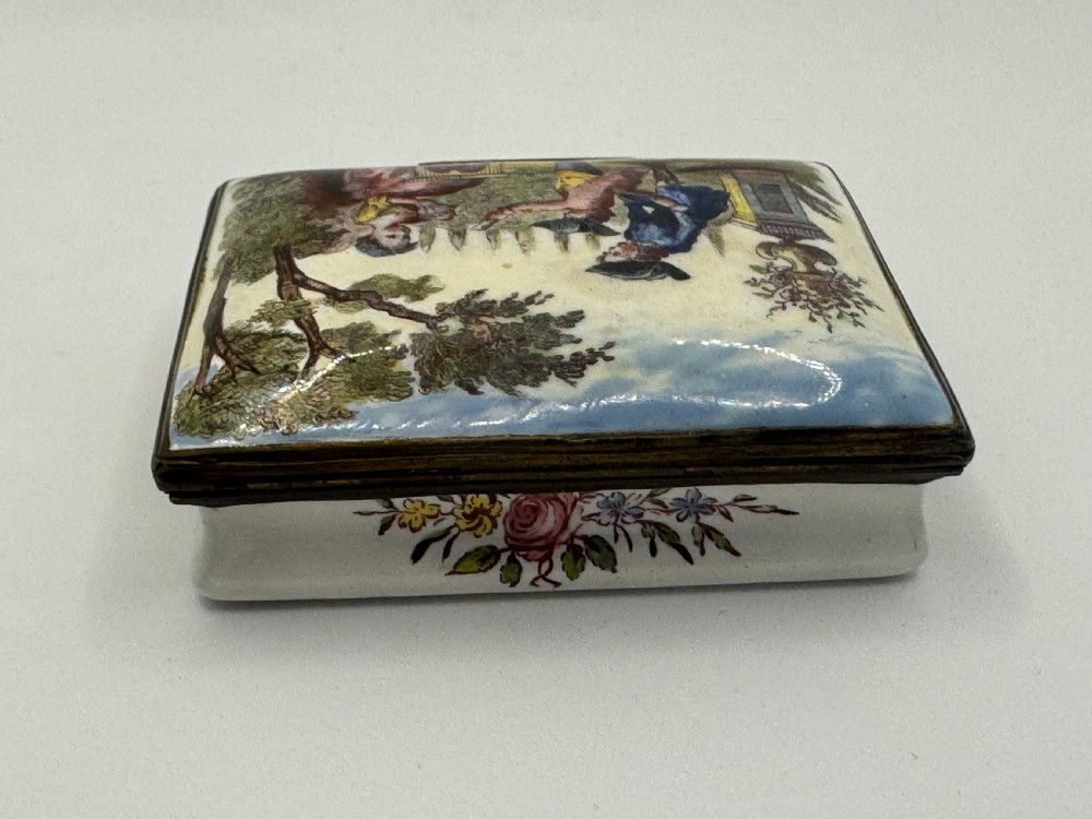 A rectangular 18th-century Bilston enamel box decorated with a painted pastoral scene on the lid and floral sprigs along the white base. View VI