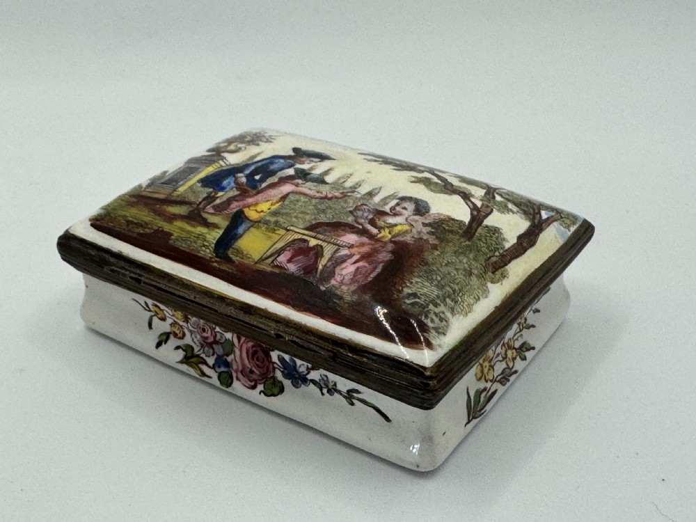 A rectangular 18th-century Bilston enamel box decorated with a painted pastoral scene on the lid and floral sprigs along the white base. View IX