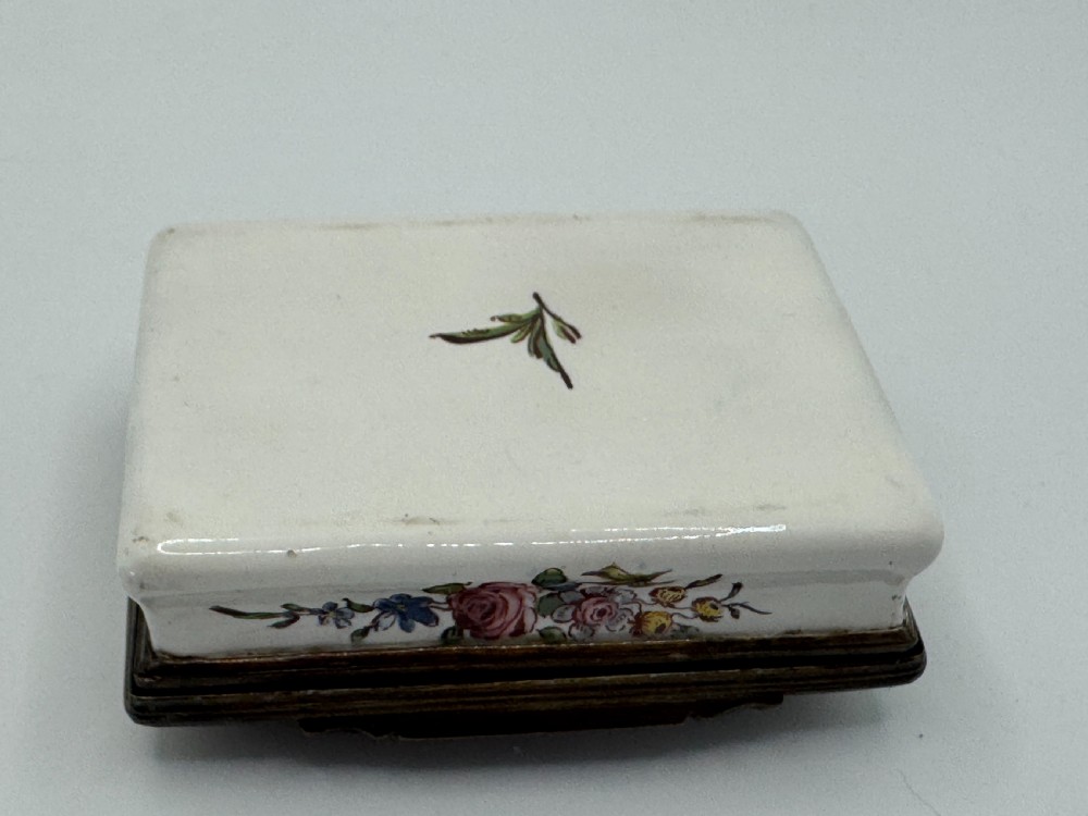 A rectangular 18th-century Bilston enamel box decorated with a painted pastoral scene on the lid and floral sprigs along the white base. View XI