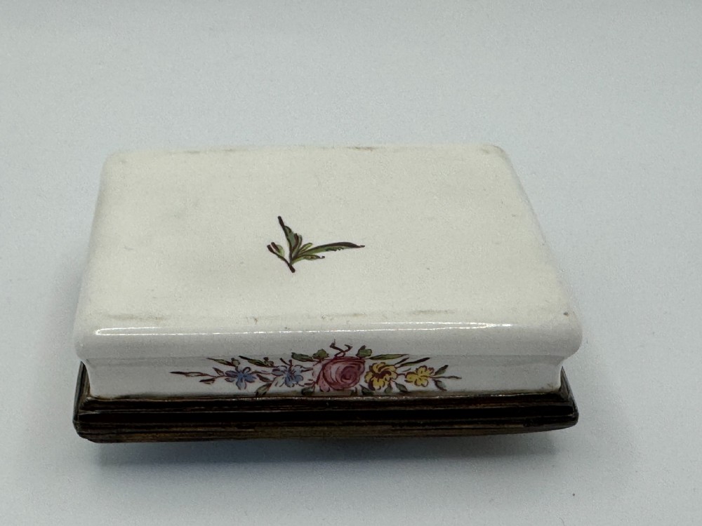 A rectangular 18th-century Bilston enamel box decorated with a painted pastoral scene on the lid and floral sprigs along the white base. View XII