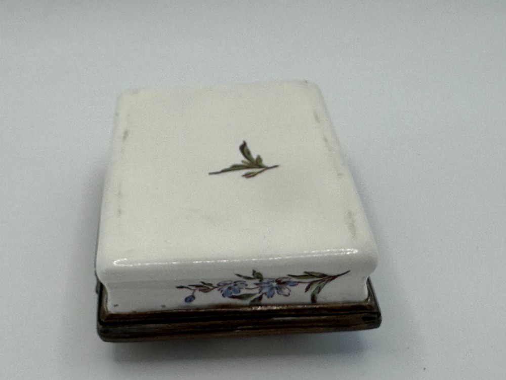 A rectangular 18th-century Bilston enamel box decorated with a painted pastoral scene on the lid and floral sprigs along the white base. View XIV