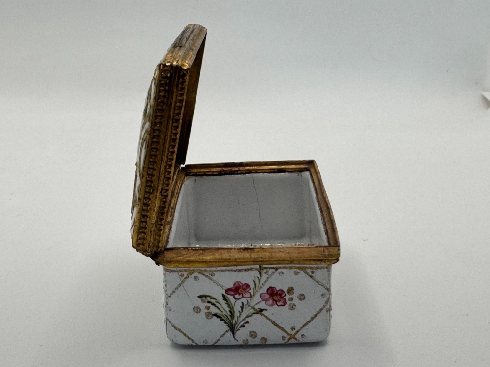 A small 19th-century rectangular enamel box decorated with a hand-painted pastoral scene surrounded by gilt scrollwork. View X