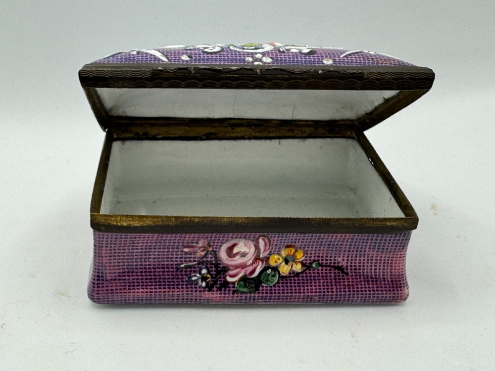 A rectangular eighteenth-century enamel box decorated with a central painted bird and fruit motif framed by white scrollwork against a purple lattice background. View V