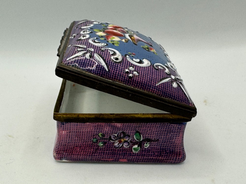 A rectangular eighteenth-century enamel box decorated with a central painted bird and fruit motif framed by white scrollwork against a purple lattice background. View VI