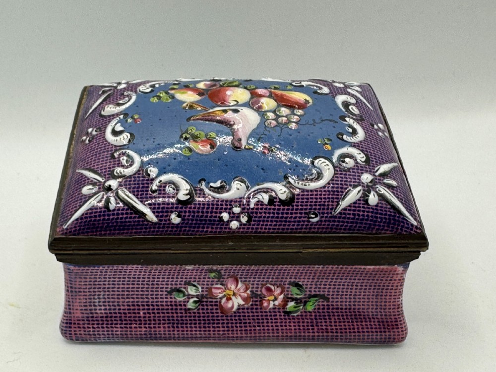 A rectangular eighteenth-century enamel box decorated with a central painted bird and fruit motif framed by white scrollwork against a purple lattice background. View VII