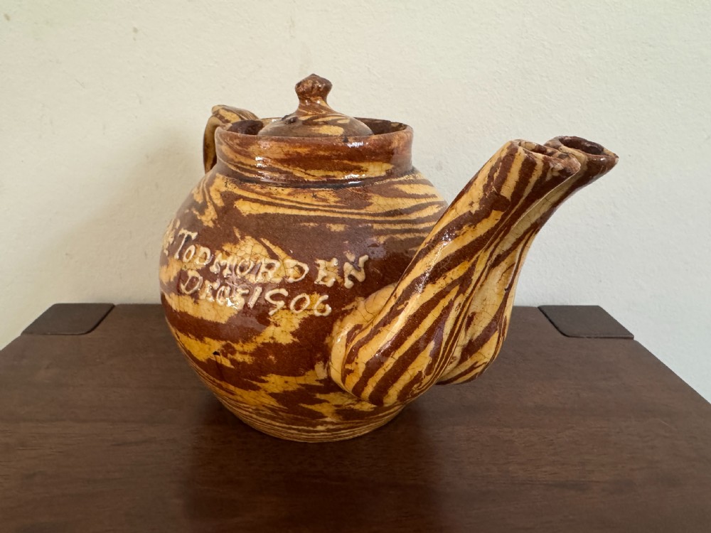 An Edwardian brown and cream marbled agateware teapot featuring twin spouts, a matching finial lid, and an inscribed date reading Todmorden Dec 1906.