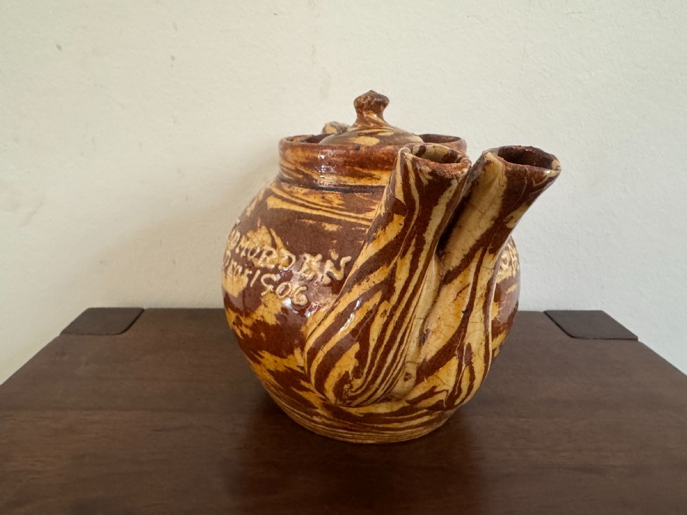 An Edwardian brown and cream marbled agateware teapot featuring twin spouts, a matching finial lid, and an inscribed date reading Todmorden Dec 1906. View II
