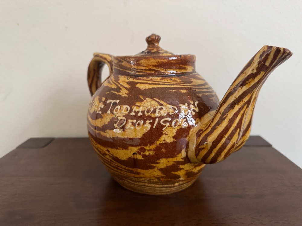 An Edwardian brown and cream marbled agateware teapot featuring twin spouts, a matching finial lid, and an inscribed date reading Todmorden Dec 1906. View XII