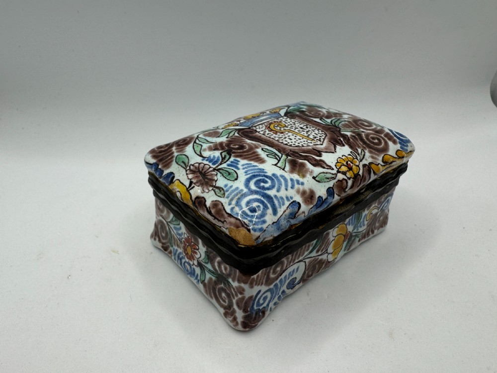 A small rectangular 17th-century Dutch Delft tin-glazed earthenware box featuring hand-painted polychrome floral motifs and an armorial shield crest. View II