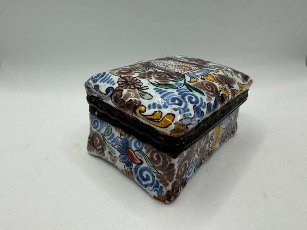 A small rectangular 17th-century Dutch Delft tin-glazed earthenware box featuring hand-painted polychrome floral motifs and an armorial shield crest. View VII