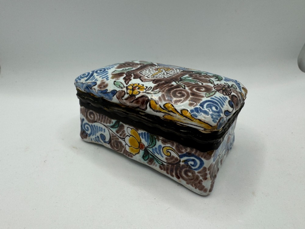 A small rectangular 17th-century Dutch Delft tin-glazed earthenware box featuring hand-painted polychrome floral motifs and an armorial shield crest. View IX