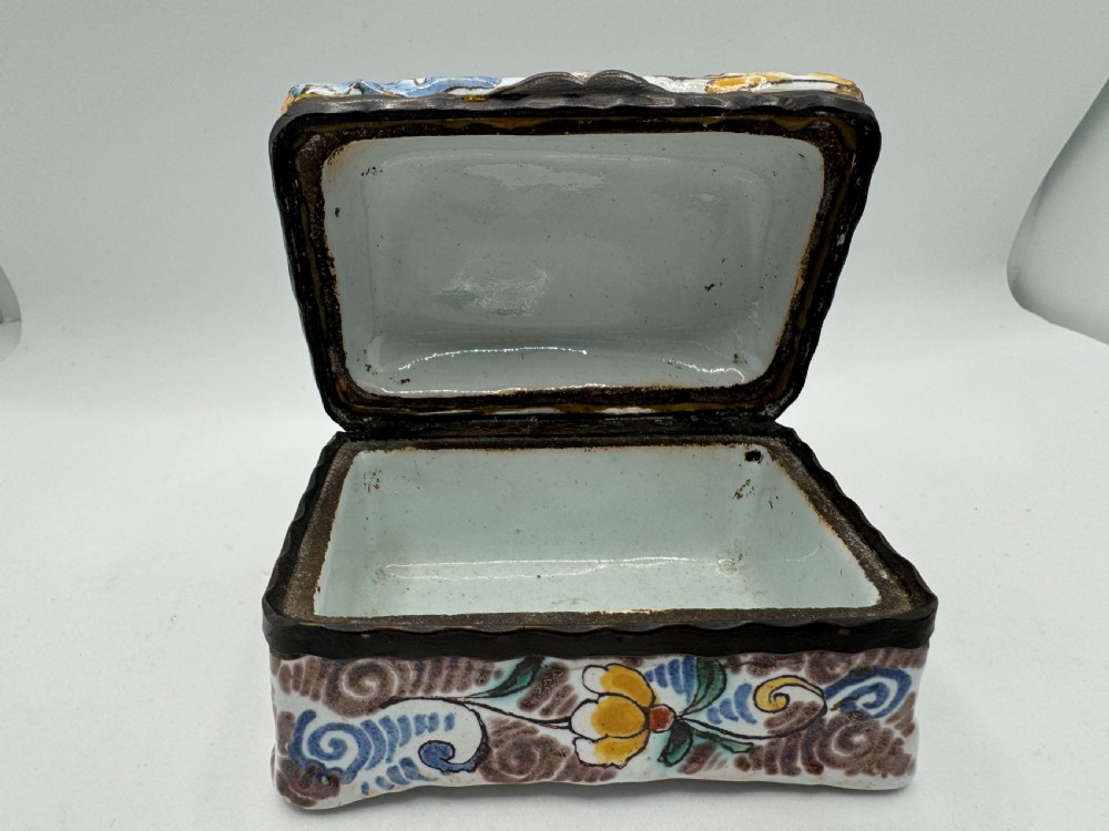 A small rectangular 17th-century Dutch Delft tin-glazed earthenware box featuring hand-painted polychrome floral motifs and an armorial shield crest. View X