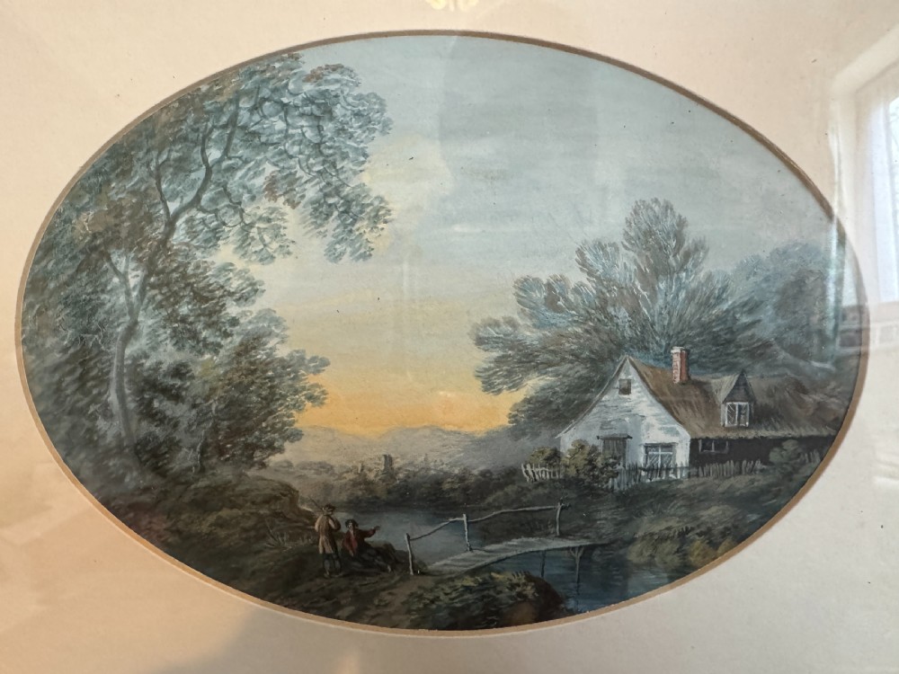 An oval 19th-century watercolour painting depicting a figure and dog crossing a stone bridge over a river, presented in a dark wood frame with a gold slip. View VIII