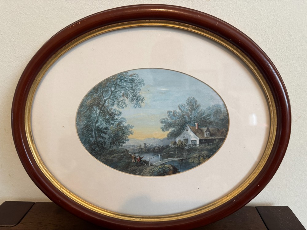 An oval 19th-century watercolour painting depicting a figure and dog crossing a stone bridge over a river, presented in a dark wood frame with a gold slip. View IX