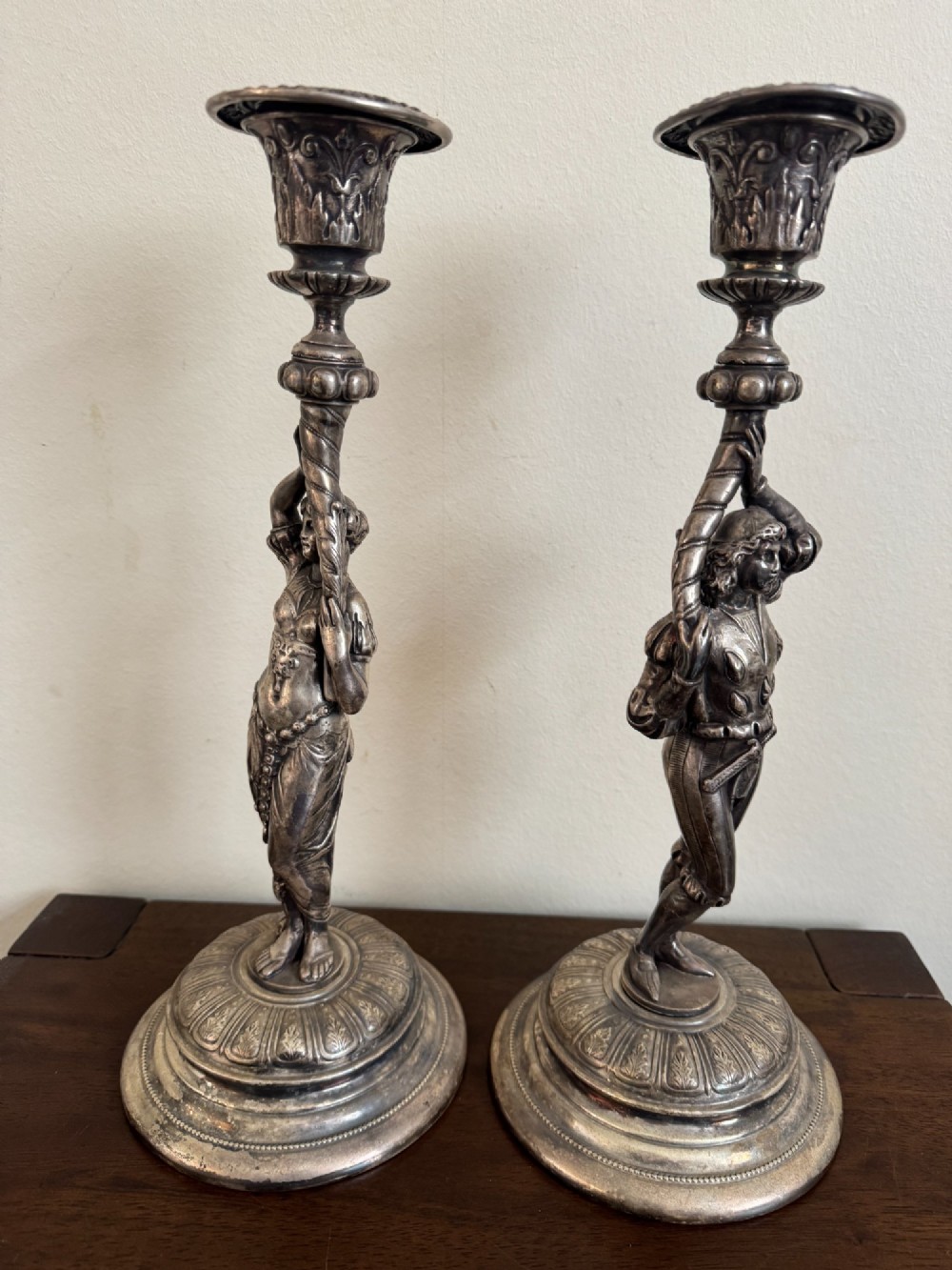A pair of antique silver-plated candlesticks featuring detailed sculpted figures of a lady and a cavalier supporting sconces on rounded bases. View II
