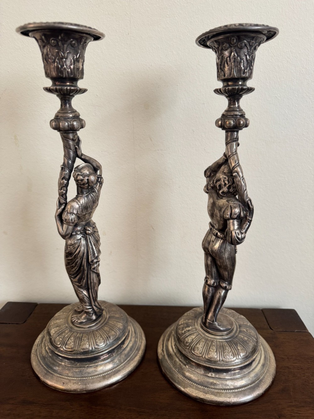 A pair of antique silver-plated candlesticks featuring detailed sculpted figures of a lady and a cavalier supporting sconces on rounded bases. View IV
