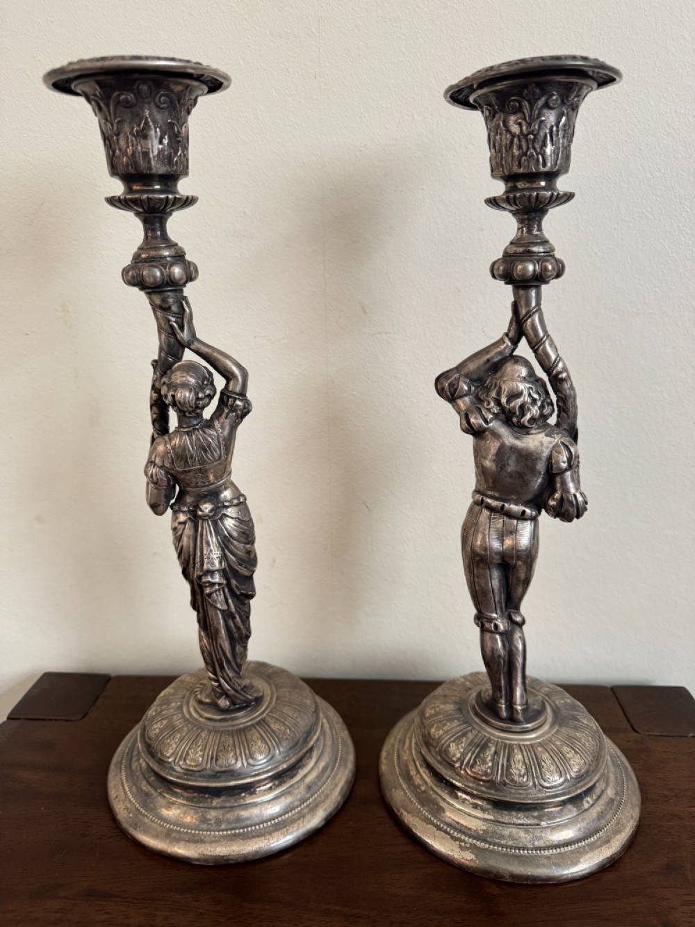 A pair of antique silver-plated candlesticks featuring detailed sculpted figures of a lady and a cavalier supporting sconces on rounded bases. View V