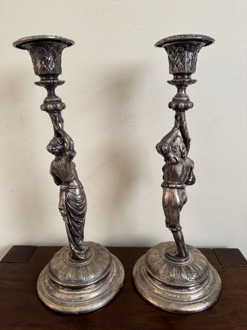 A pair of antique silver-plated candlesticks featuring detailed sculpted figures of a lady and a cavalier supporting sconces on rounded bases. View VI