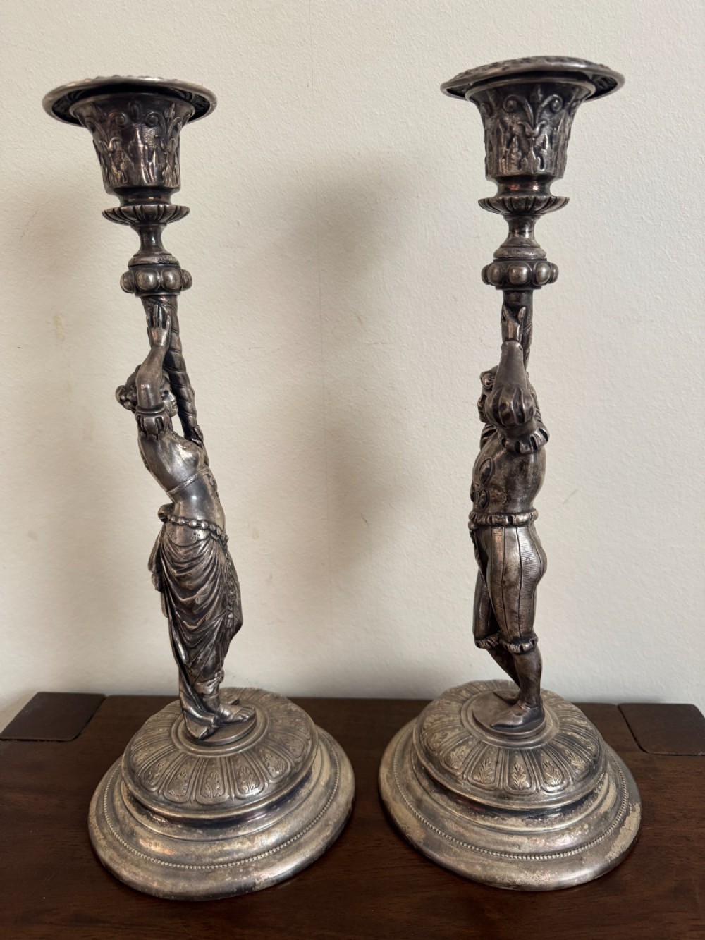 A pair of antique silver-plated candlesticks featuring detailed sculpted figures of a lady and a cavalier supporting sconces on rounded bases. View VII