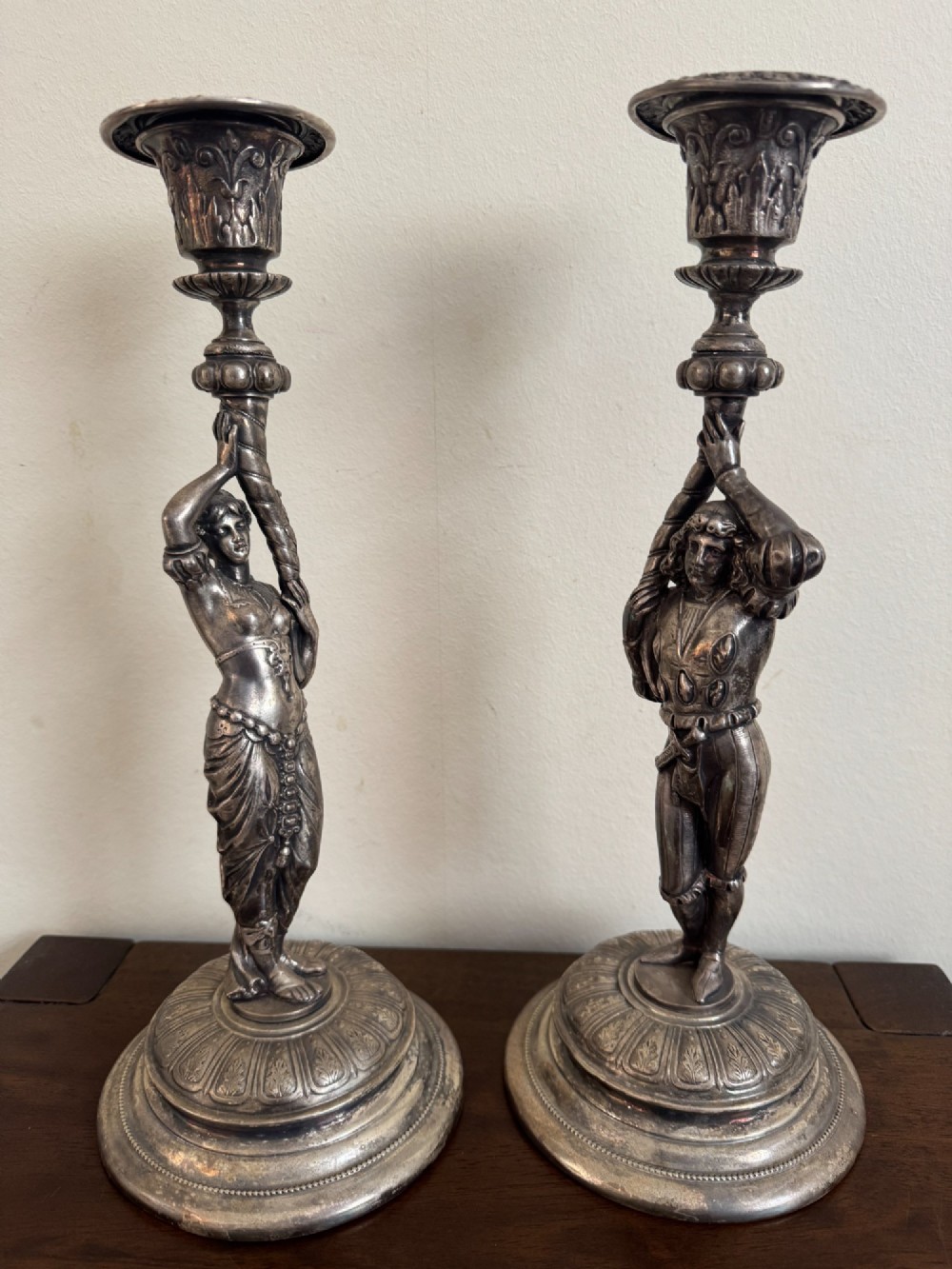 A pair of antique silver-plated candlesticks featuring detailed sculpted figures of a lady and a cavalier supporting sconces on rounded bases. View VIII