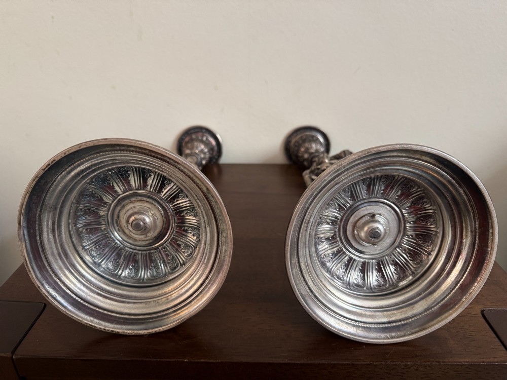 A pair of antique silver-plated candlesticks featuring detailed sculpted figures of a lady and a cavalier supporting sconces on rounded bases. View IX