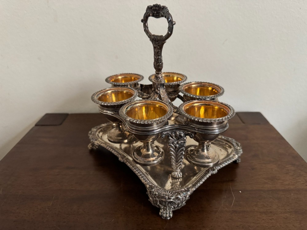 A Georgian sterling silver egg cruet stand holding six gilt-lined silver egg cups on a raised tray base with a central handle. View III