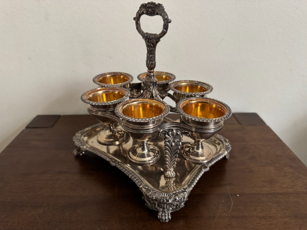 A Georgian sterling silver egg cruet stand holding six gilt-lined silver egg cups on a raised tray base with a central handle. View V