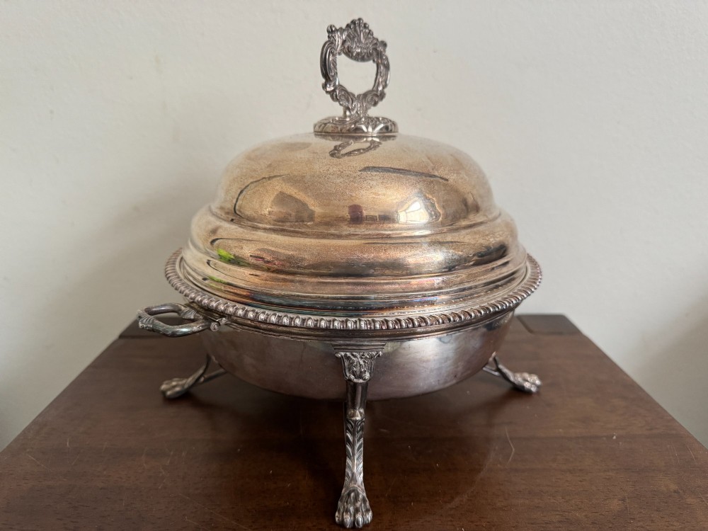A George III sterling silver domed supper dish featuring cast handles, gadrooned borders, and a matching stand supported by paw feet. View IV