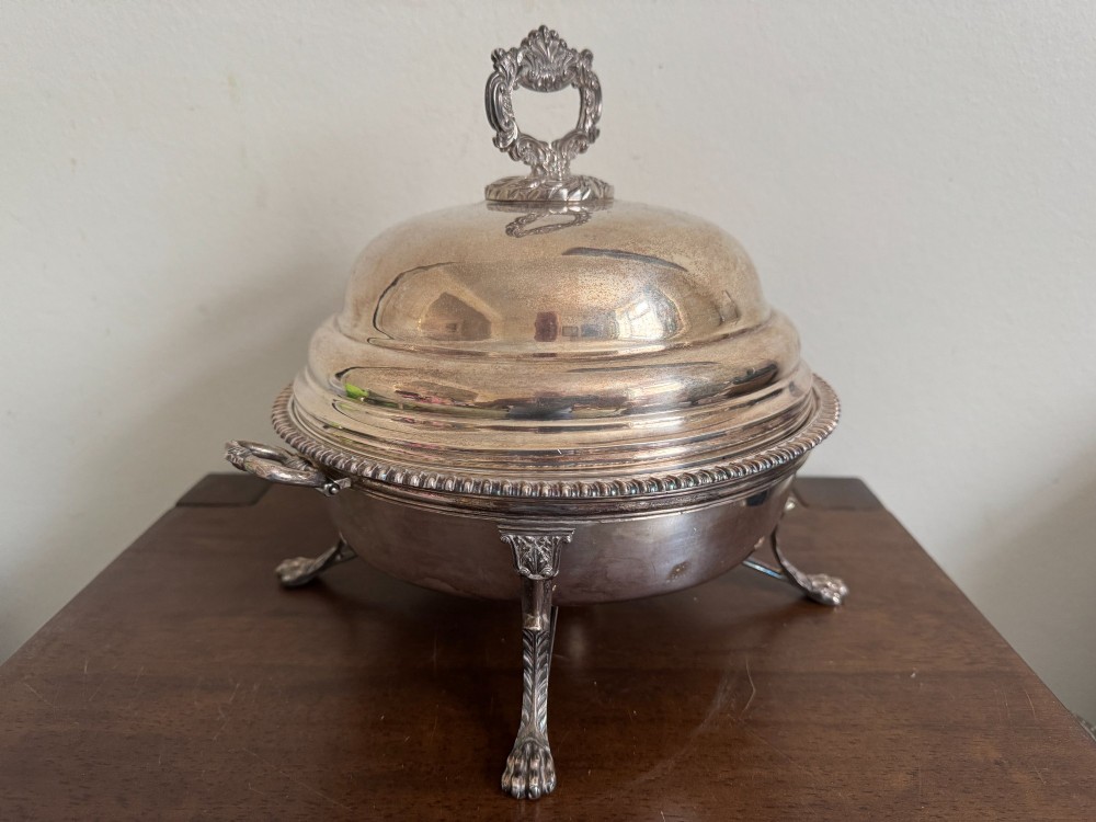 A George III sterling silver domed supper dish featuring cast handles, gadrooned borders, and a matching stand supported by paw feet. View VIII