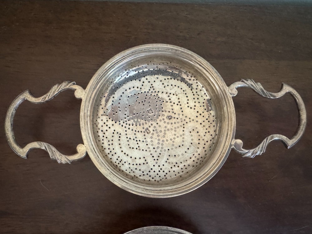 A matched pair of George III sterling silver lemon strainers featuring pierced geometric bowl patterns and dual side handles. View VI