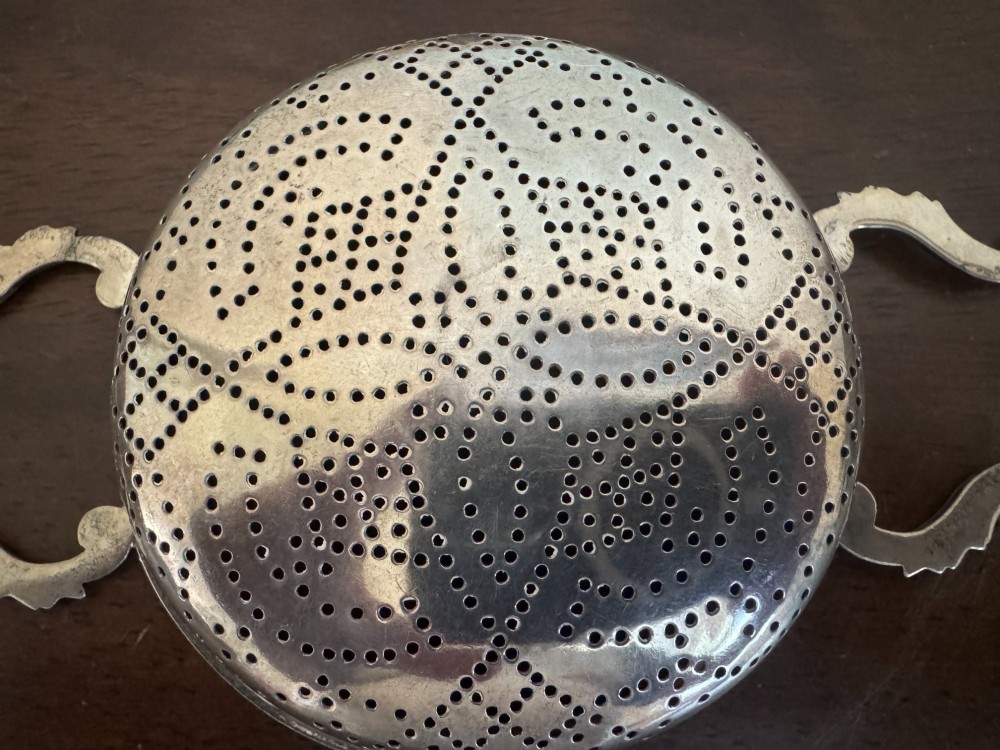 A matched pair of George III sterling silver lemon strainers featuring pierced geometric bowl patterns and dual side handles. View XI