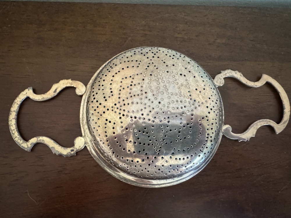 A matched pair of George III sterling silver lemon strainers featuring pierced geometric bowl patterns and dual side handles. View XII