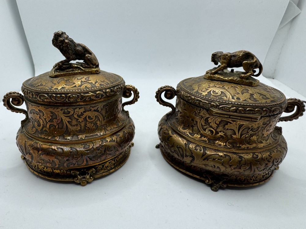 A pair of nineteenth-century gilt-metal jewellery caskets with acanthus leaf relief carving, side handles, and dog finials on the lids.