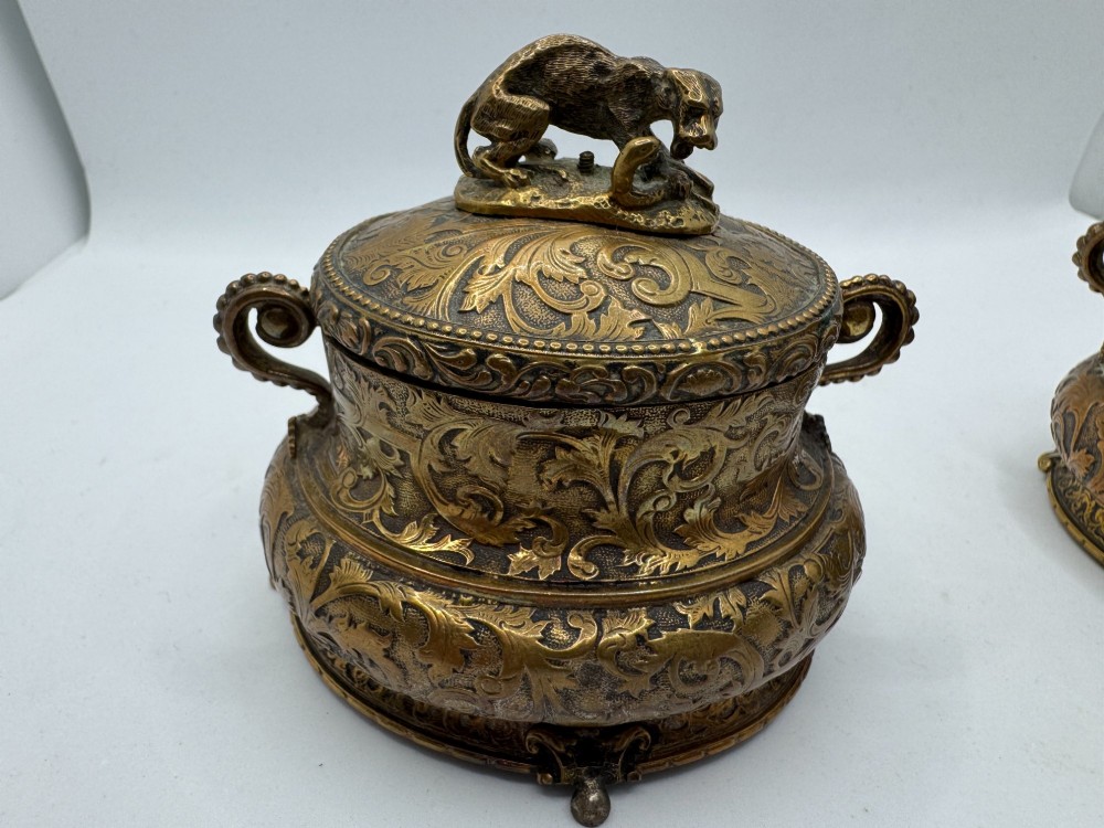 A pair of nineteenth-century gilt-metal jewellery caskets with acanthus leaf relief carving, side handles, and dog finials on the lids. View V