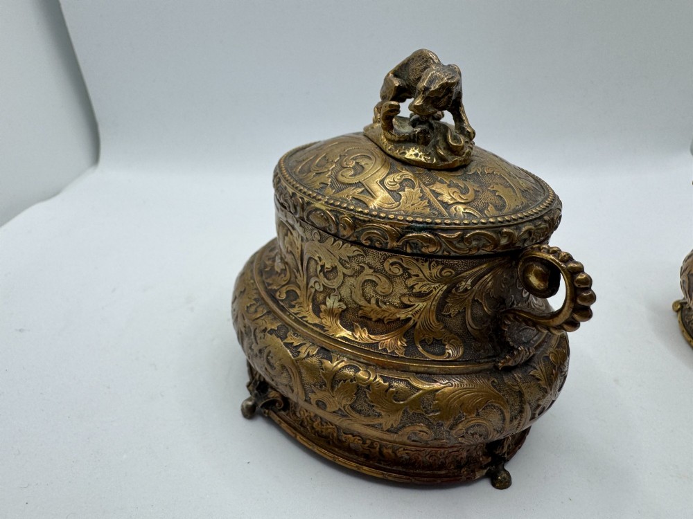 A pair of nineteenth-century gilt-metal jewellery caskets with acanthus leaf relief carving, side handles, and dog finials on the lids. View X
