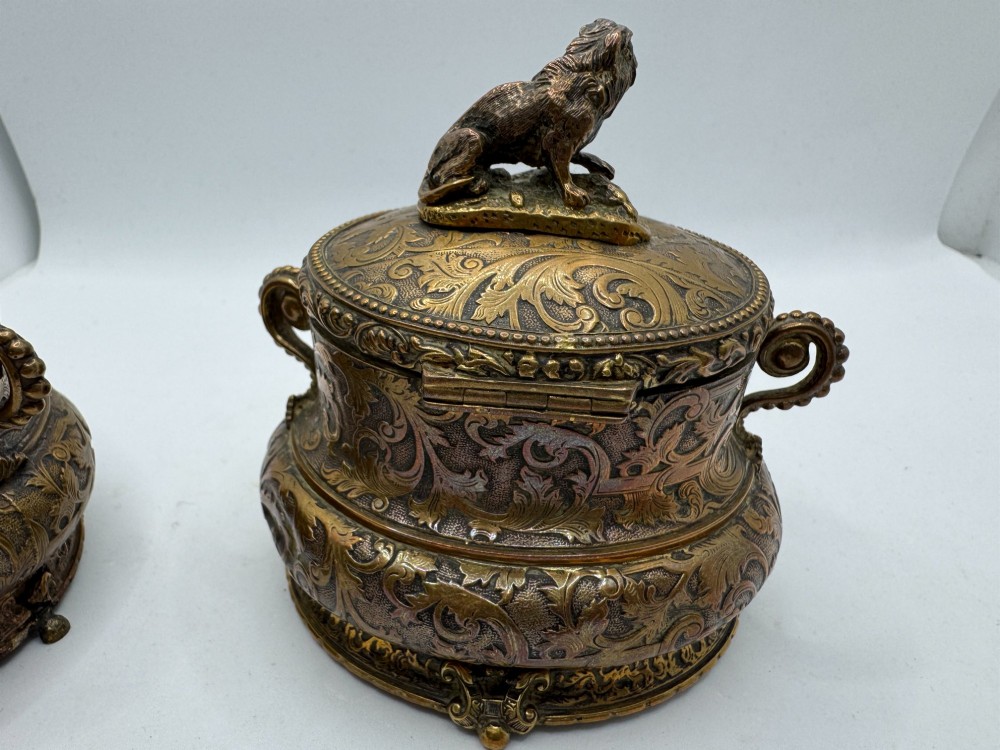 A pair of nineteenth-century gilt-metal jewellery caskets with acanthus leaf relief carving, side handles, and dog finials on the lids. View XIV