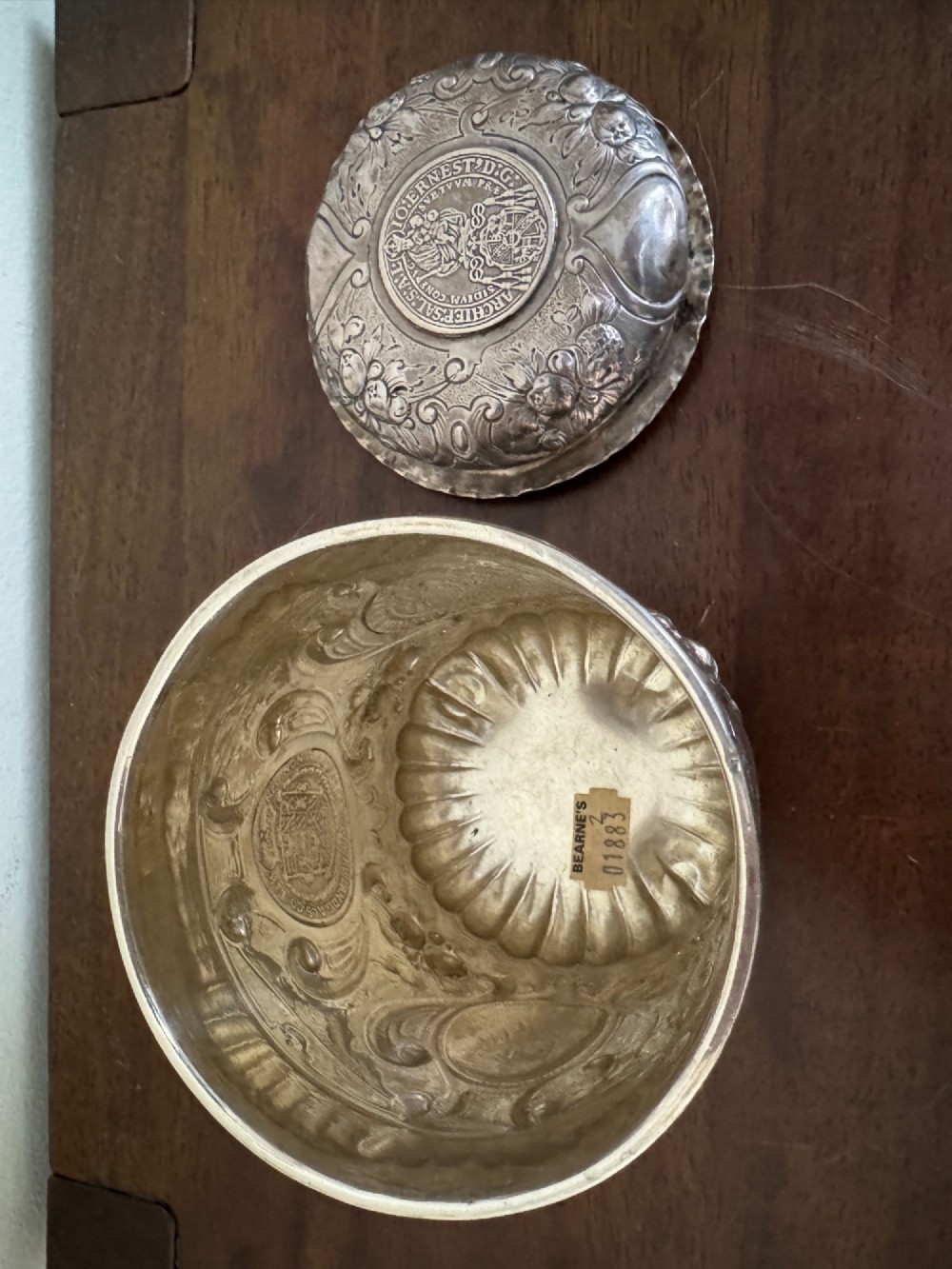 A sterling silver lidded beaker decorated with chased repousse scrollwork, embedded silver thaler coins, and standing on ball feet. View XI
