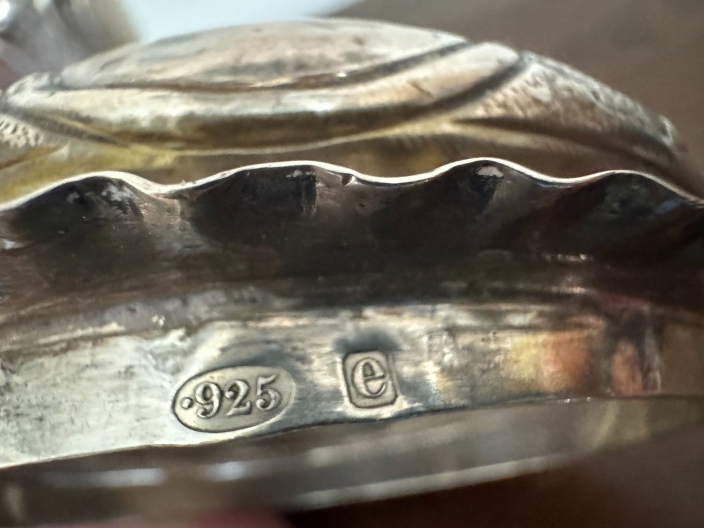 A sterling silver lidded beaker decorated with chased repousse scrollwork, embedded silver thaler coins, and standing on ball feet. View XIV