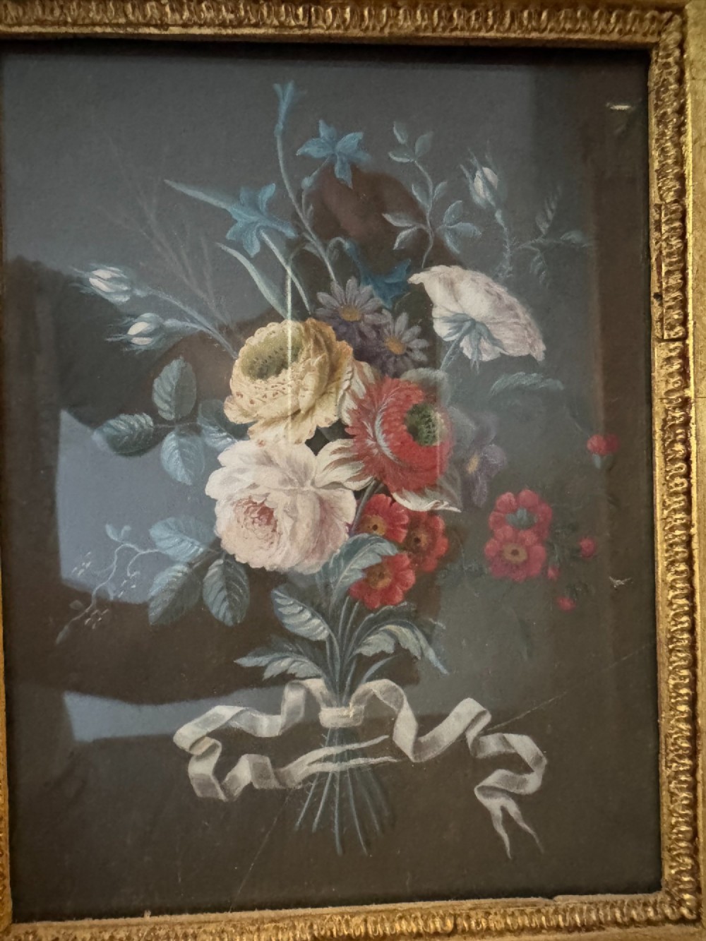 A pair of framed antique gouache paintings on dark backgrounds depicting floral bouquets tied with white ribbons, set in gilded frames. View VI