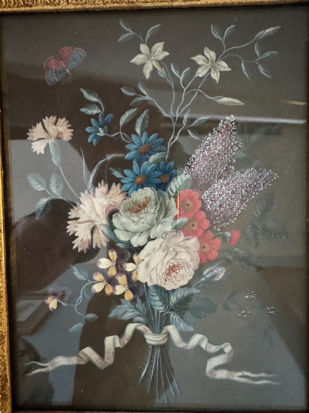 A pair of framed antique gouache paintings on dark backgrounds depicting floral bouquets tied with white ribbons, set in gilded frames. View X
