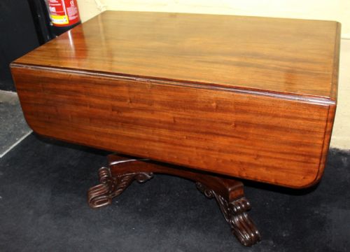 fig 1. A polished mahogany William IV drop-leaf centre table featuring a rectangular top, drop sides, and a carved pedestal base with scroll feet.