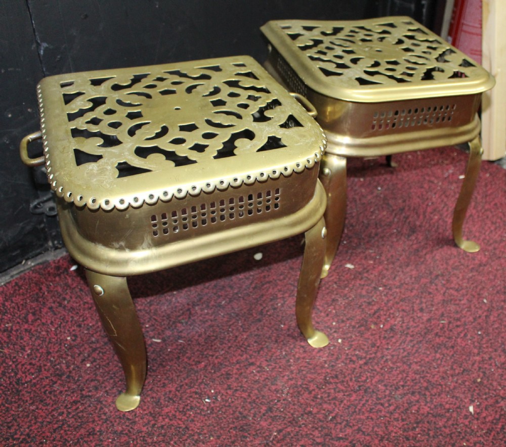 A pair of early 19th-century brass footman trivets featuring pierced lattice tops, side handles, and cabriole legs. View II