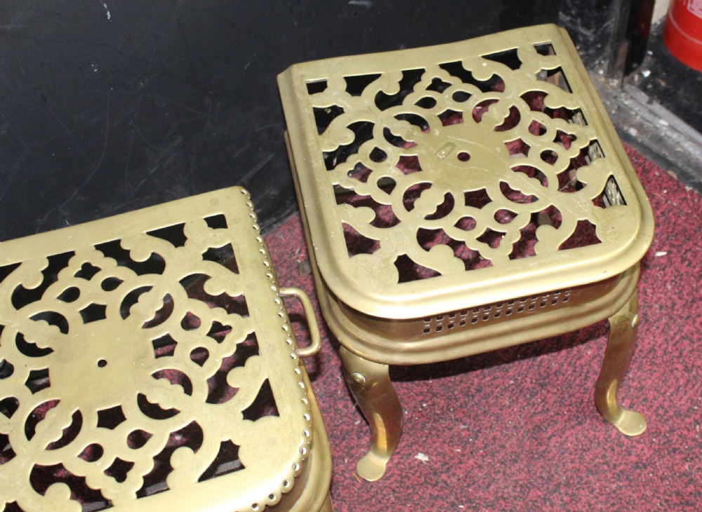 A pair of early 19th-century brass footman trivets featuring pierced lattice tops, side handles, and cabriole legs. View VI