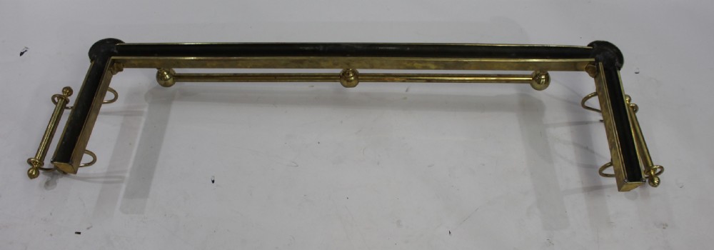An antique solid brass low fireplace fender featuring a central tubular top rail with three spherical supports and elevated outswept tool rests on both sides. View IV