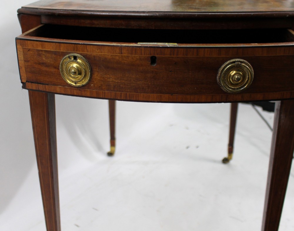A George III mahogany Pembroke table featuring two hinged drop leaves, crossbanded inlay work, a single drawer with a brass ring handle, and square tapered legs with brass castors. View II
