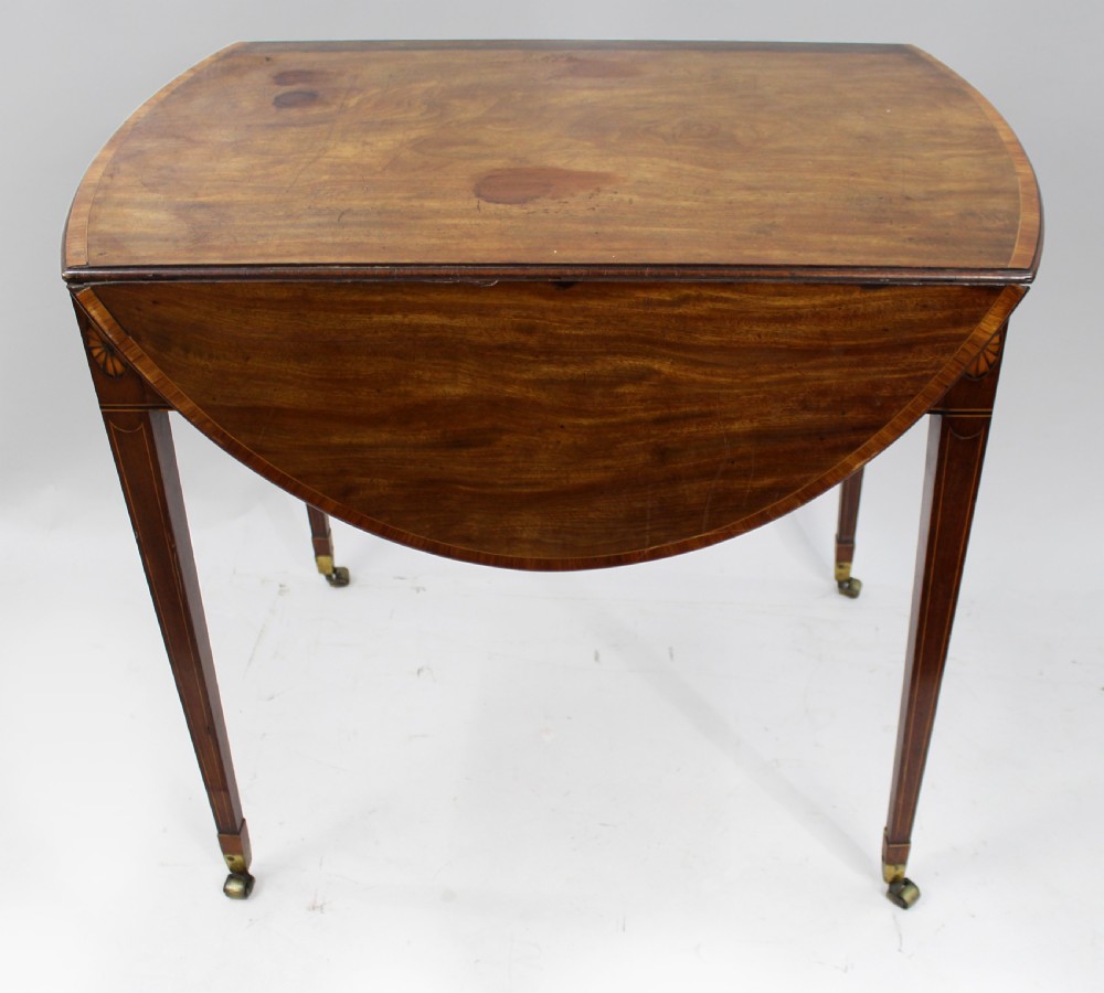 A George III mahogany Pembroke table featuring two hinged drop leaves, crossbanded inlay work, a single drawer with a brass ring handle, and square tapered legs with brass castors. View III