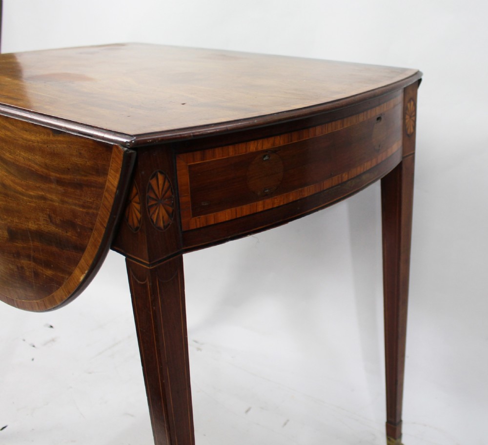 A George III mahogany Pembroke table featuring two hinged drop leaves, crossbanded inlay work, a single drawer with a brass ring handle, and square tapered legs with brass castors. View V